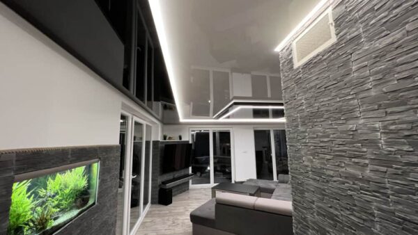 Černý lesklý napínaný strop s minimalistickým LED osvětlením v moderním obývacím pokoji  Designový prvek, který opticky zvětšuje prostor a dodává interiéru hloubku 