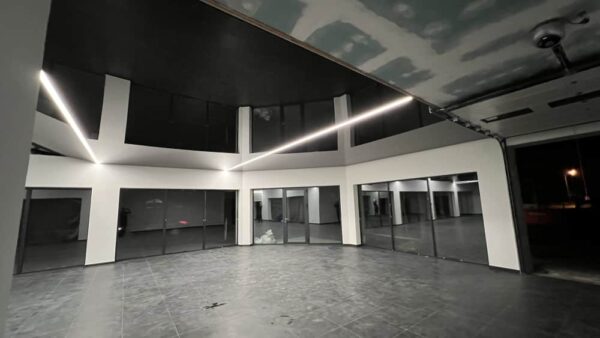 Černý lesklý napínaný strop s integrovanými světelnými liniemi LED v hale společnosti PK Technik s r o 