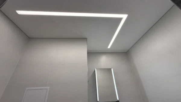 Matný napínaný strop s integrovaným LED osvětlením ve tvaru L v moderní koupelně