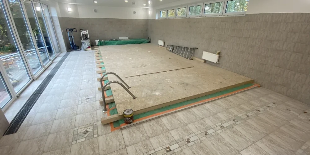 Zakrytý bazén pro bezpečnou montáž napínaného stropu Bazén v interiéru zakrytý OSB deskami pro bezpečný pohyb montážního lešení při instalaci napínaného stropu