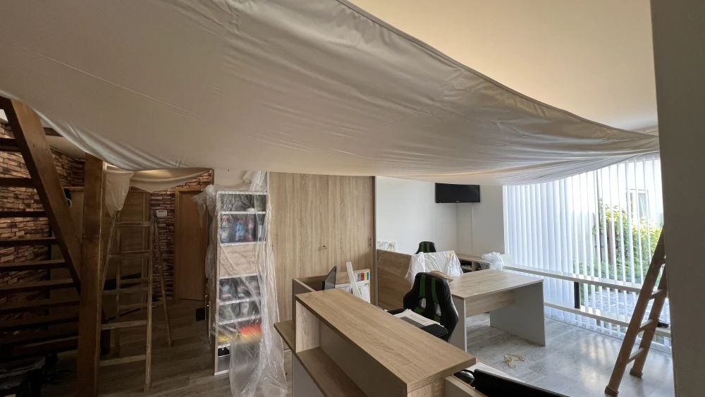  Instalace napínaného stropu ve světlé kanceláři během montáže